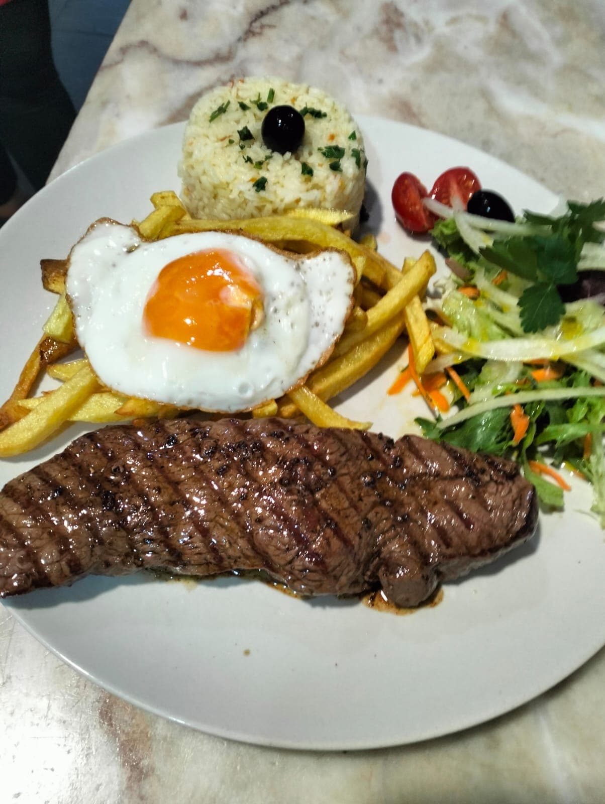 Bife grelhado na grelha de carvão com ovo e acompanhamentos